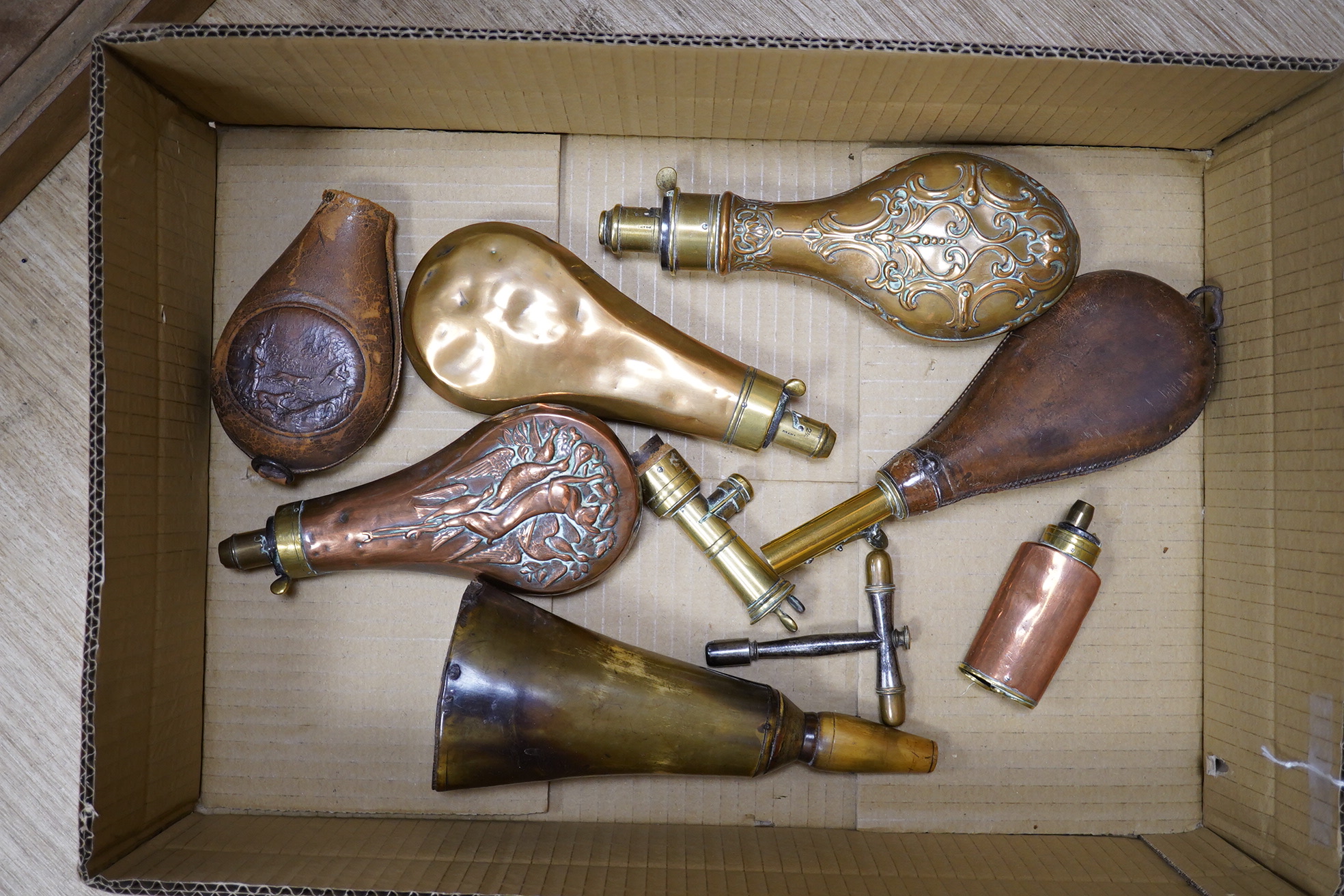 Four assorted copper powder flasks comprising; a three-way flask by Sykes (dented), ‘three horses head’ flask by Hawksley and two others, together with two leather shot flasks, a horn powder flask and a percussion nipple